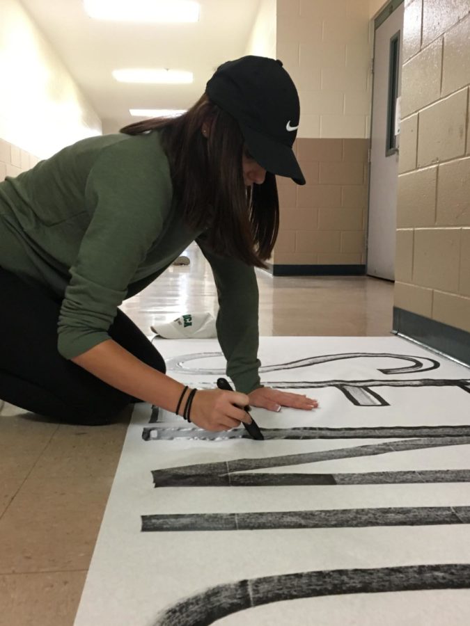 A leadership member works on a banner for the Pink-Out pep rally.