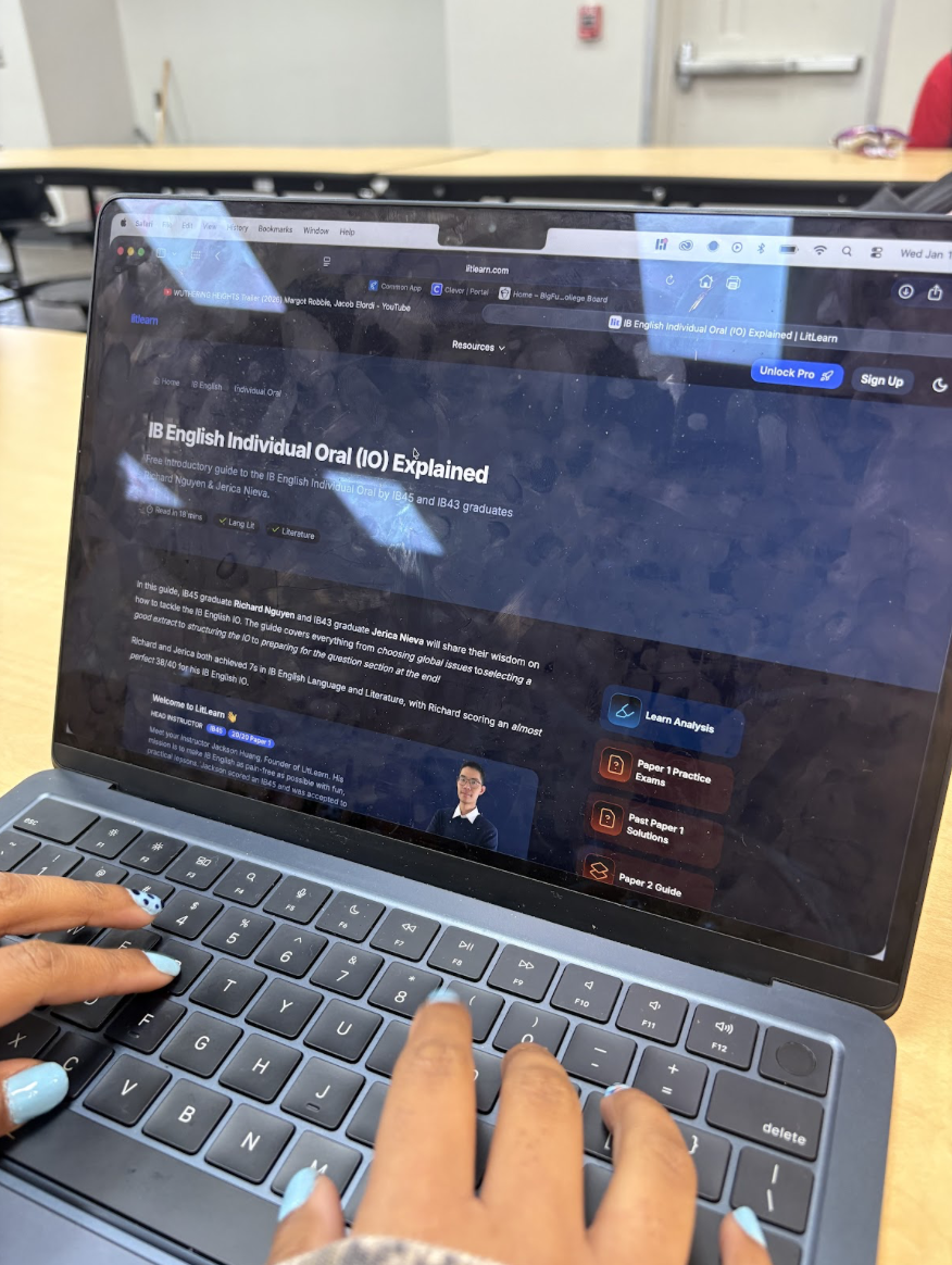 A pair of hands searching up information of IB orals with a table and chairs in the background.